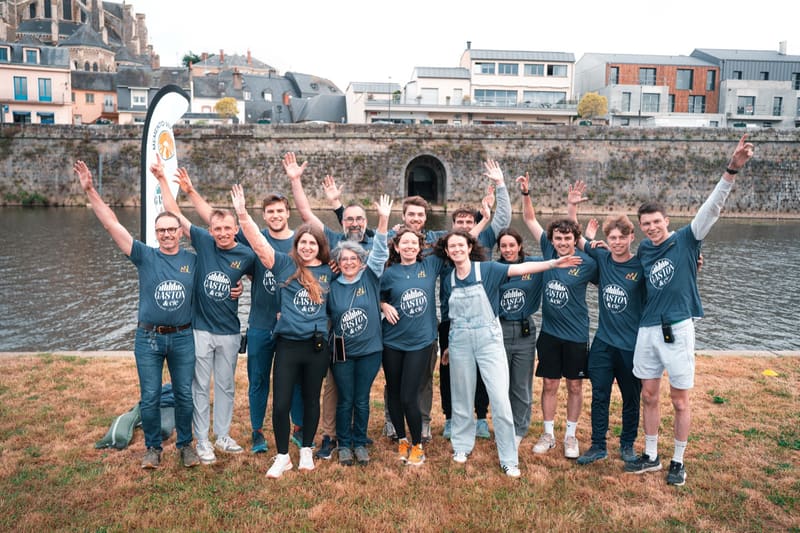 Les bénévoles de l'édition 2025 alignés bras levés devant la Mayenne