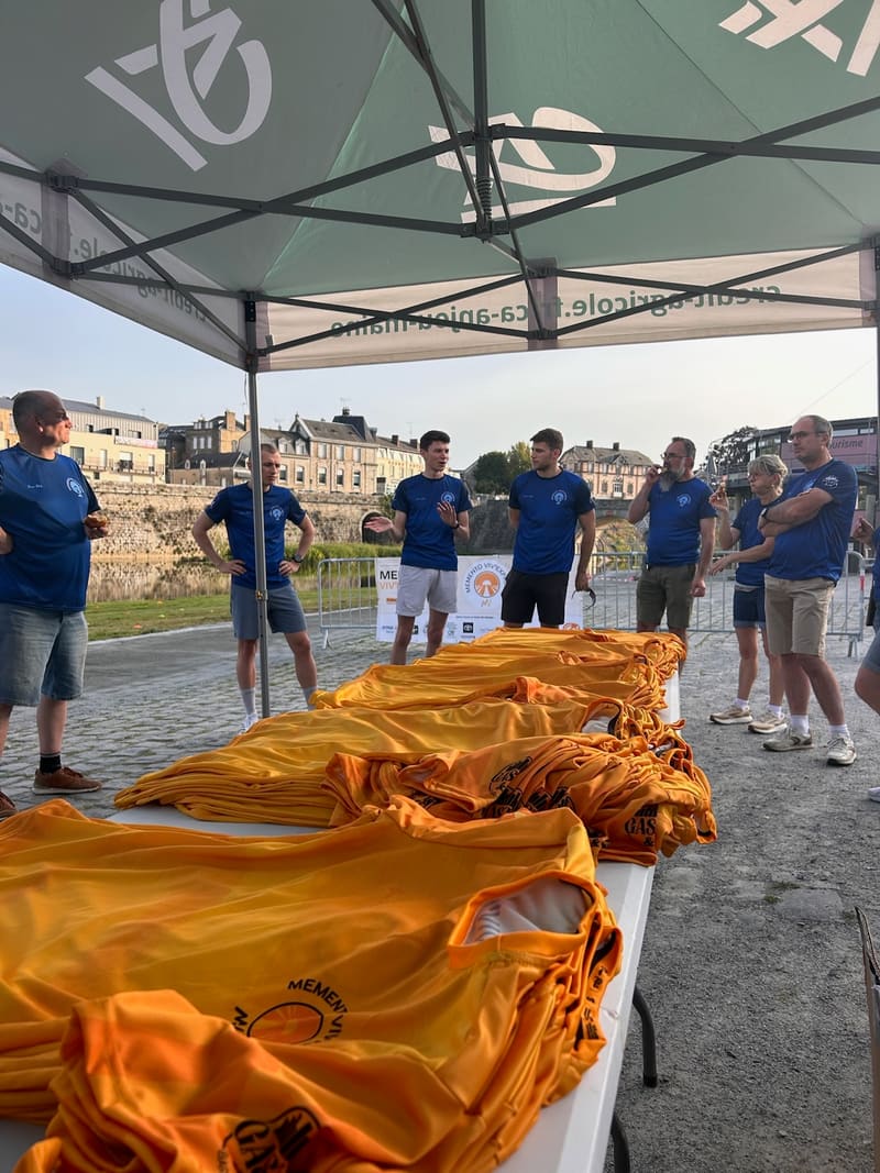 Les bénévoles en bleu au petit matin sous le barnum, t-shirts jaunes pliés prêts à distribuer
