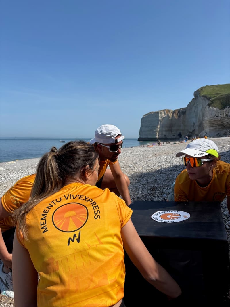 Trois participants concentrés autour d'une caisse d'épreuve sur la plage