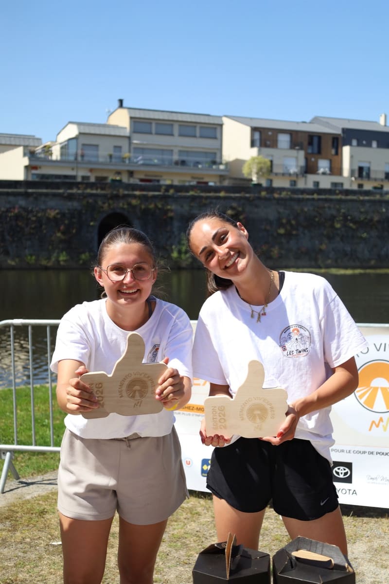 Le binôme vainqueur brandit ses trophées pouce en bois « Édition 2026 »
