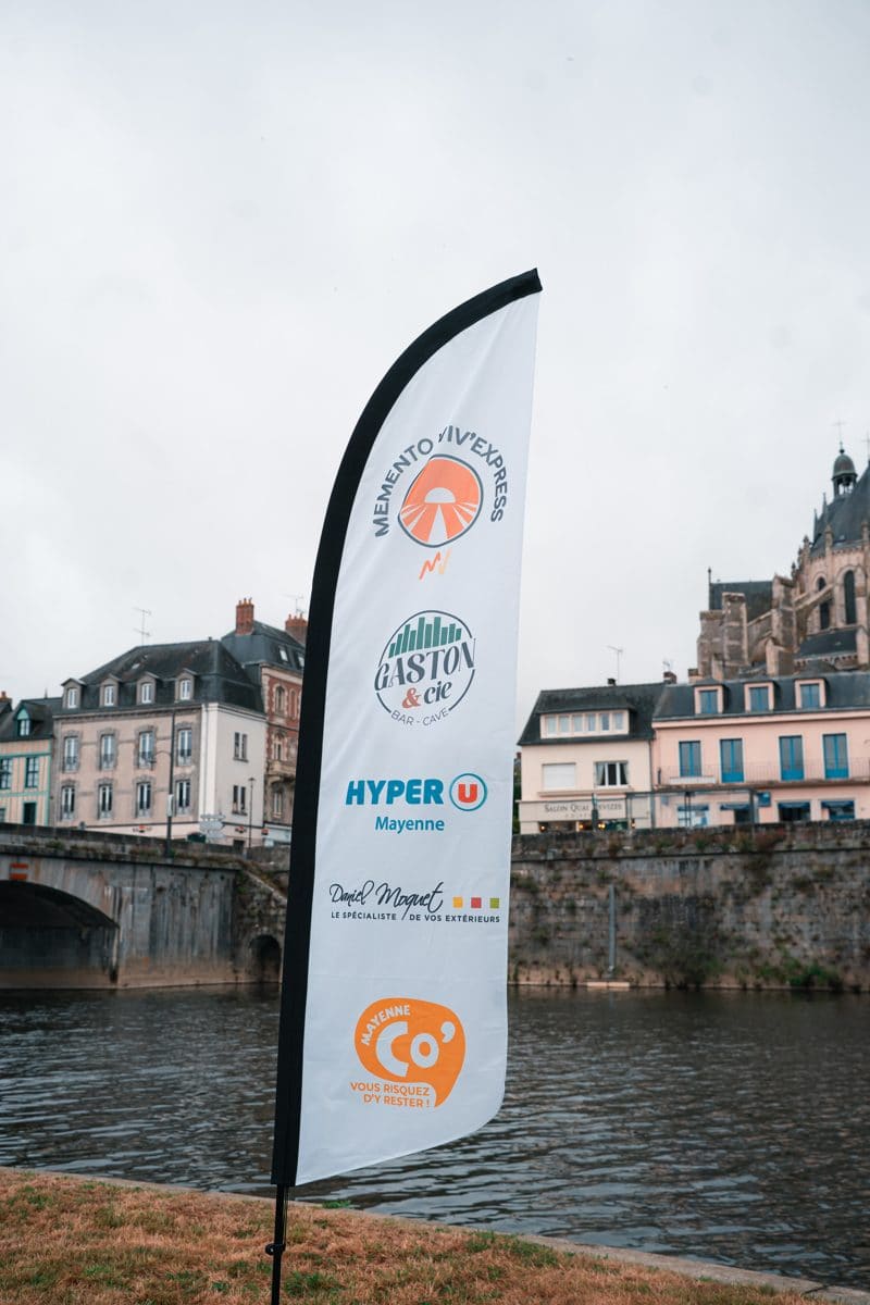 Drapeau Viv'Express avec les logos des sponsors, au bord de la Mayenne